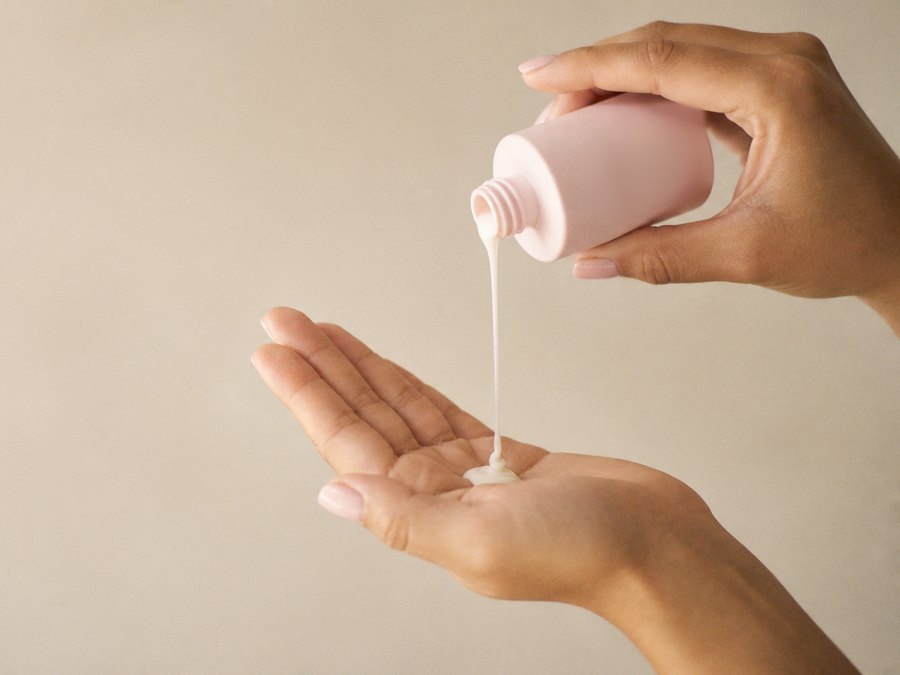 Mãos aplicando um produto de cuidado com a pele